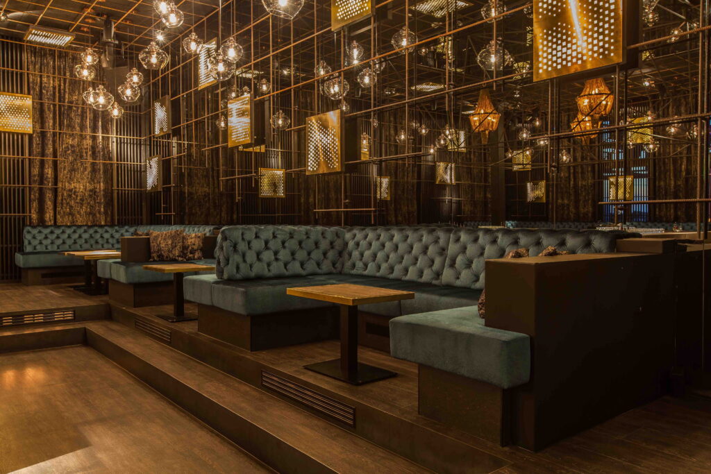 Elegante Lounge mit gepolsterten Sitzb&auml;nken, warmem Licht und Spiegelw&auml;nden, die eine einladende Atmosph&auml;re schaffen.